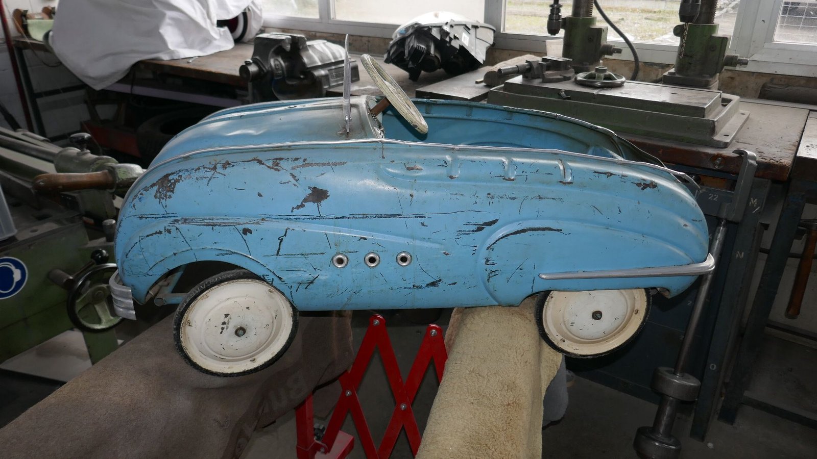 Auf einem Tisch steht ein blaues Spielzeugauto mit weißen Rädern.